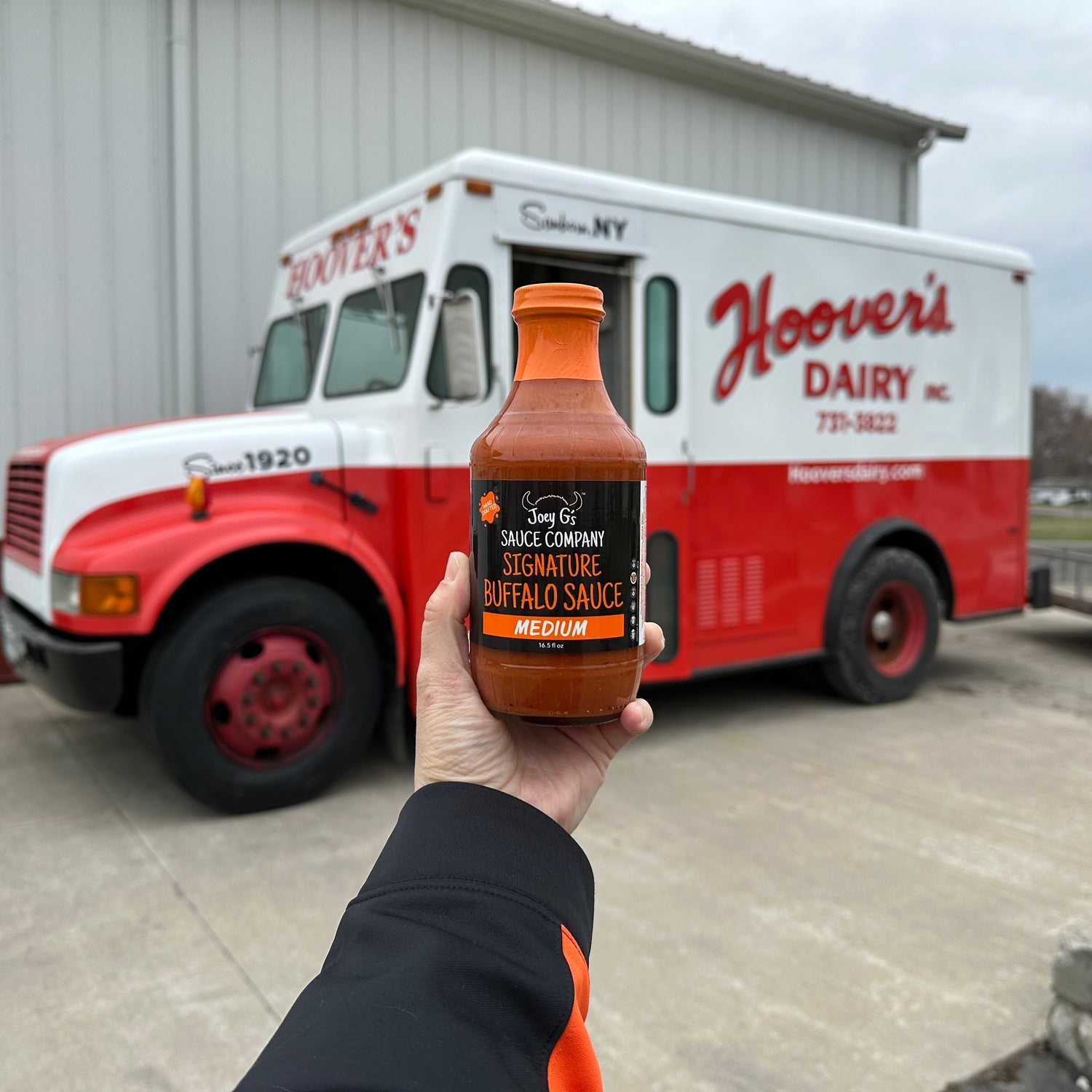 Bottle of Joey G's Medium Signature Buffalo Sauce with Hoover's Dairy Truck in background